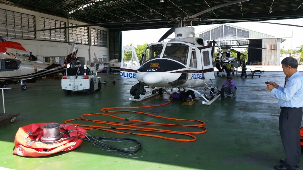Collapsible helibucket and long-line suspension cables staged on an aviation hangar floor for routine maintenance and inspection