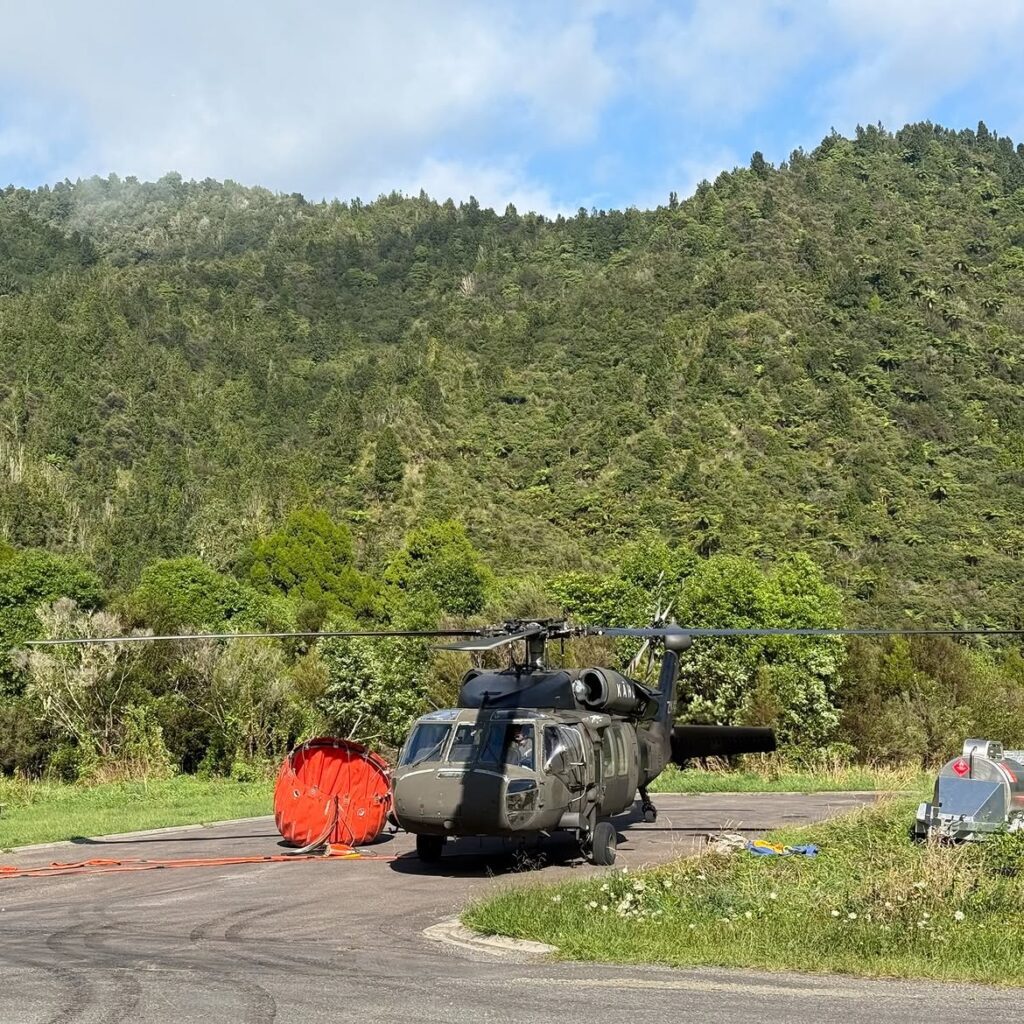 Heavy-lift Black Hawk firefighting helicopter staged on the tarmac next to a collapsible water bucket