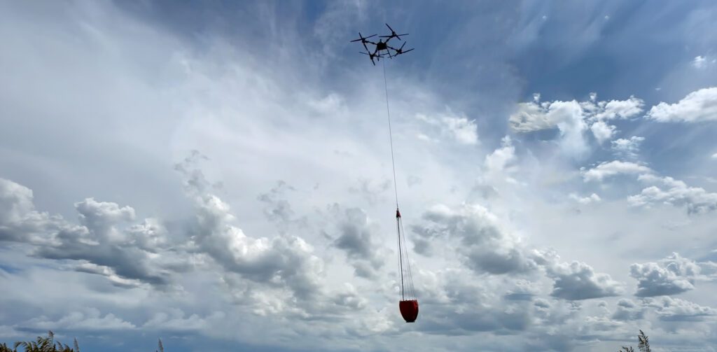 Unmanned aerial vehicle drone deploying a suspended firefighting water bucket