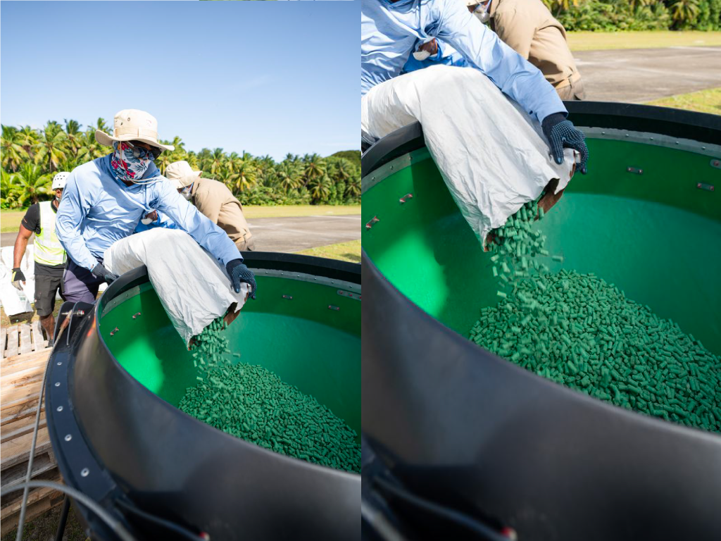 Ground crew manually loading green granular bait into the hopper of a Ground-Effect aerial baiting bucket