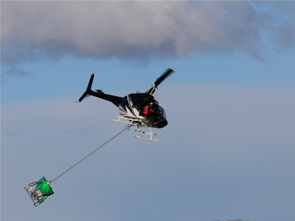 Agricultural banking in flight while carrying an underslung granular spreader bucket