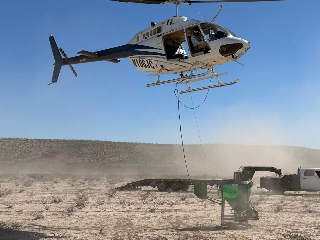 Helicopter loading a fertilizer spreader bucket