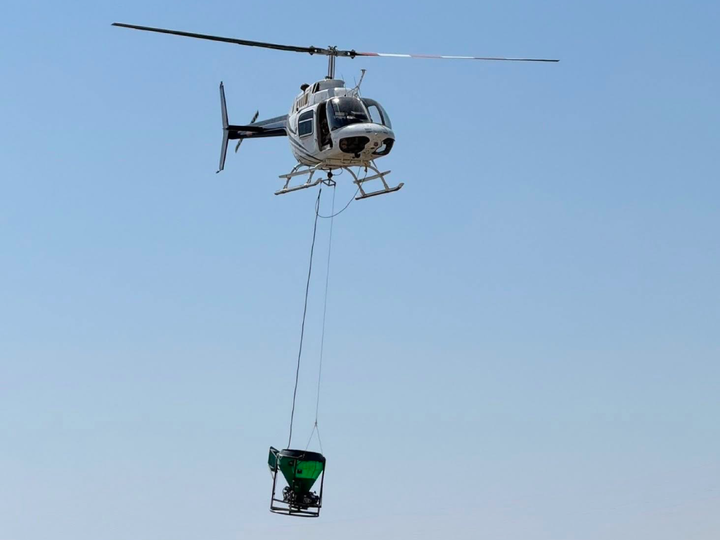 Ground-Effect aerial seeding bucket low over flat, arid terrain